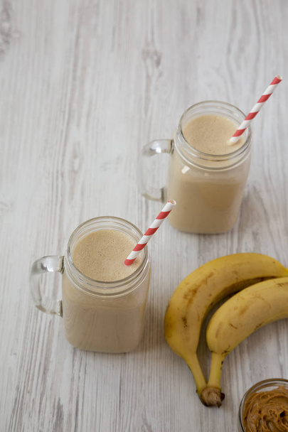 Peanut butter banana smoothie in glass jars on a white wooden ta - Foto, Imagem