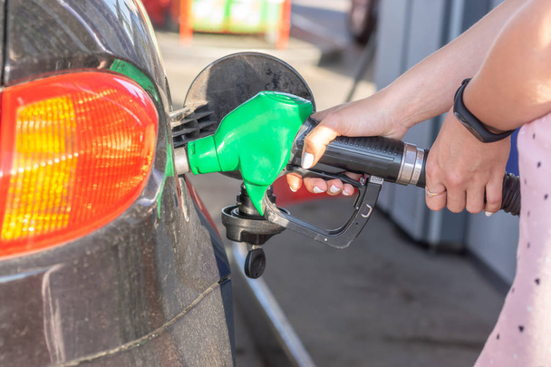 Gas pump nozzle in the fuel tank of bronze car, refuel petroleum to vehicle at gas station.  - Photo, Image