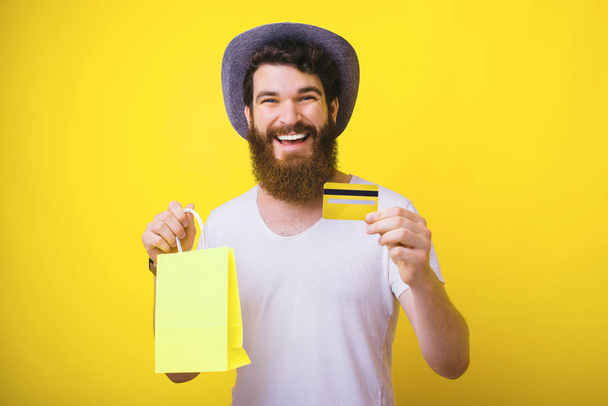 Portrait of smiling happy man holding yellow credit card and sho - Foto, Bild