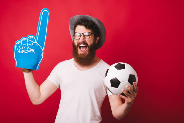 Hombre sorprendido con barba en camiseta blanca gritando y sosteniendo soc
 - Foto, Imagen