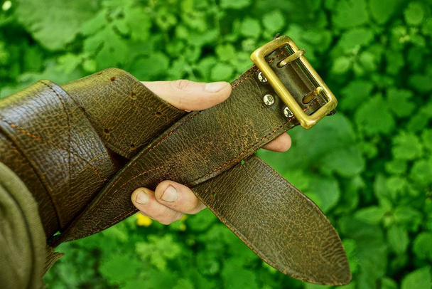 Brown strap wound on the hand on the background of green grass - Foto, immagini