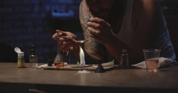 Чоловік нагріває ліки в ложці
 - Фото, зображення