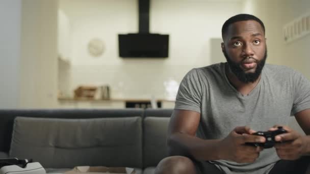 Smiling black man playing video game at home kitchen. - Footage, Video