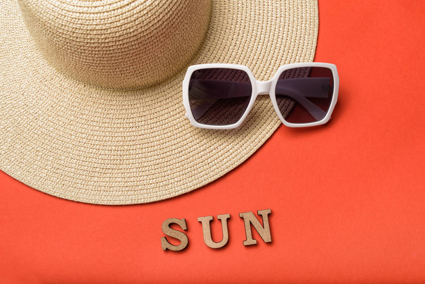 Word Sun from wooden letters. Sun glasses and hat. Live coral background. Travel concept - Foto, imagen