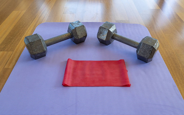 Dumbbells en oefen band op een Yogamat voor een thuis workout - Foto, afbeelding