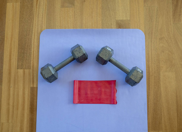 Banda de halteres e exercícios em um tapete de ioga para um treino em casa
 - Foto, Imagem