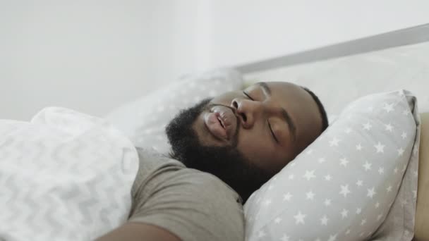 Hombre negro durmiendo en la cama por la mañana. Cabeza de adulto joven cubierta con almohada
. - Imágenes, Vídeo
