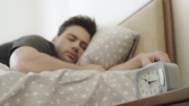 Handsome man listening alarm clock through dream. Man turning off alarm clock. - Footage, Video