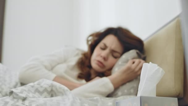 Sick woman feeling bad in bedroom. Ill female person sneezing in bed. - Felvétel, videó