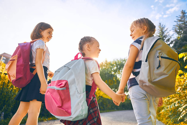 Las chicas con mochila van a la escuela
 - Foto, Imagen