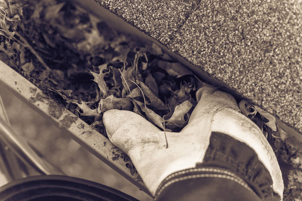 Imagem filtrada vista superior mão em luvas na escada limpeza folhas secas da sarjeta na América
 - Foto, Imagem