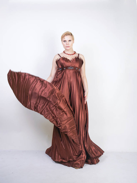 young pregnant girl in a long brown pleated evening dress - Photo, Image