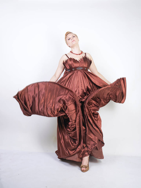 young pregnant girl in a long brown pleated evening dress - Foto, afbeelding