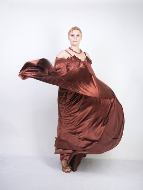 joven embarazada en un vestido de noche largo plisado marrón
 - Foto, imagen