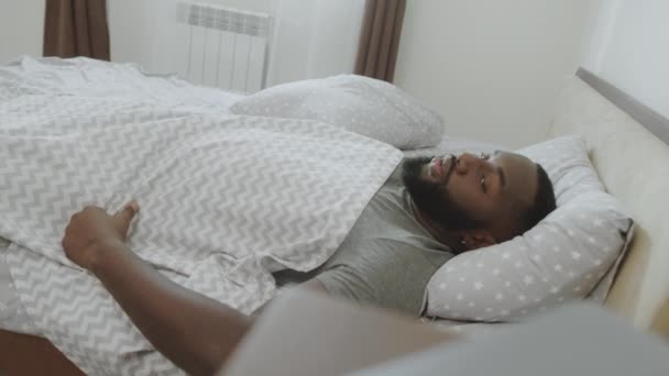 Der afrikanische Mann wacht am Morgen langsam auf. Junge männliche Person verschlafen am Morgen. - Filmmaterial, Video