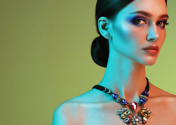 beautiful fashion model wearing elegant jewelry in color light - Fotó, kép