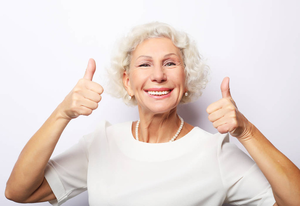 Lifestyle, emotion and people concept: Elderly happy woman giving a thumb up and looking at the camera - Foto, immagini