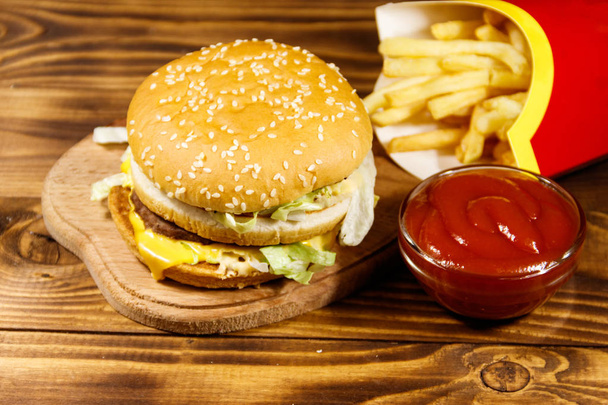 Вкусный большой гамбургер с картошкой фри и кетчупом на деревянном столе - Фото, изображение