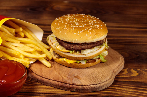Вкусный большой гамбургер с картошкой фри и кетчупом на деревянном столе - Фото, изображение