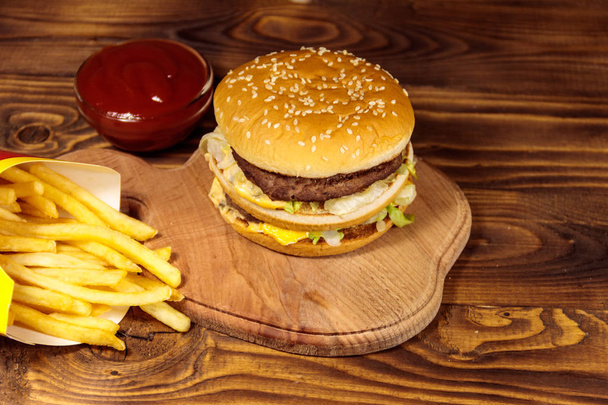 Pyszne duże hamburgery z frytkami i ketchupem na drewnianym stole - Zdjęcie, obraz
