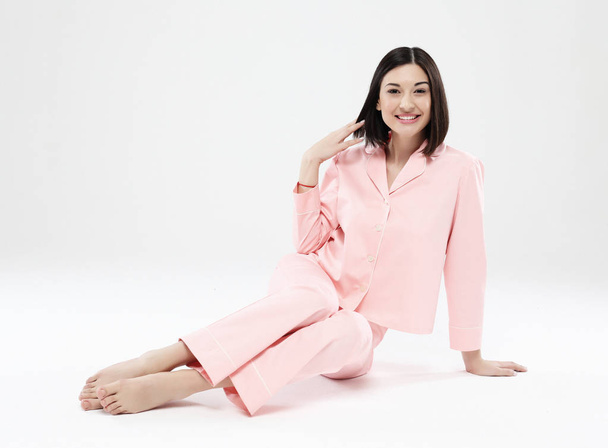 beautiful brunette woman dressed in pink pajamas sitting on the floor - Valokuva, kuva