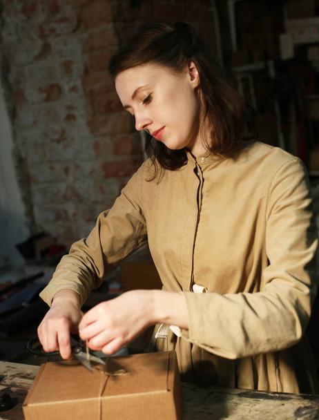 young woman folds packing box in sewing workshop - Fotografie, Obrázek