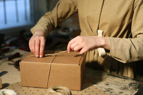 young woman folds packing box in sewing workshop - Фото, изображение