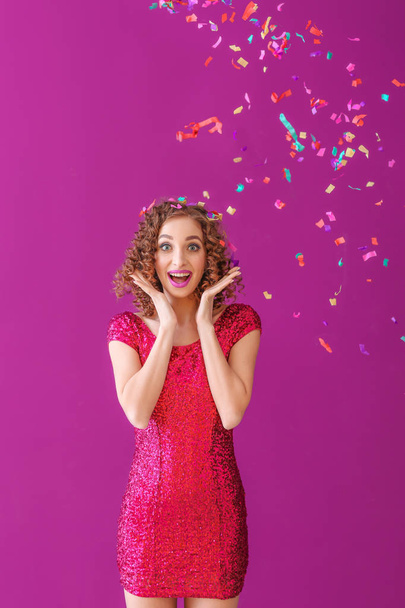 Surprised young woman with confetti on color background - Φωτογραφία, εικόνα