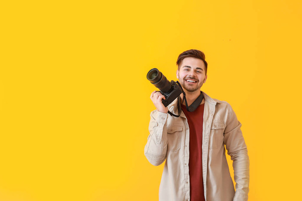 Jonge mannelijke fotograaf op kleur achtergrond - Foto, afbeelding