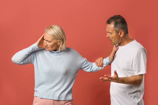 Quarrelling middle-aged couple on color background - Foto, afbeelding