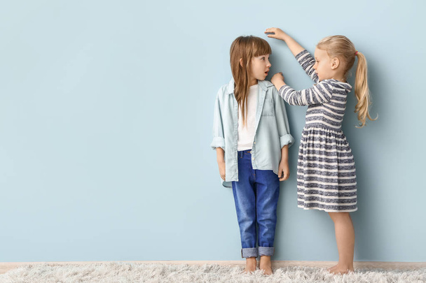 Маленькие девочки измеряют высоту рядом со стеной
 - Фото, изображение