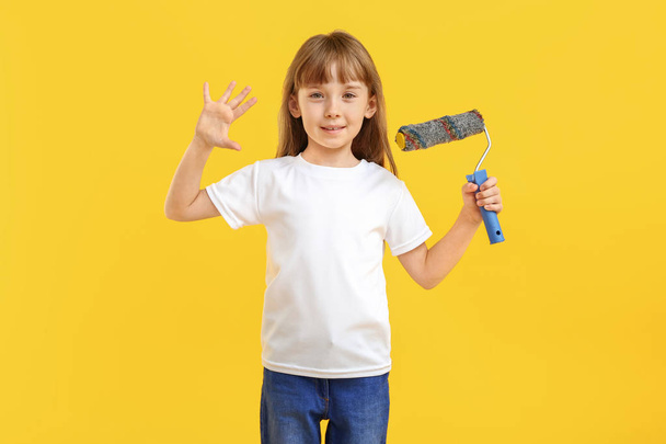 Little girl with paint roller on color background - Fotó, kép