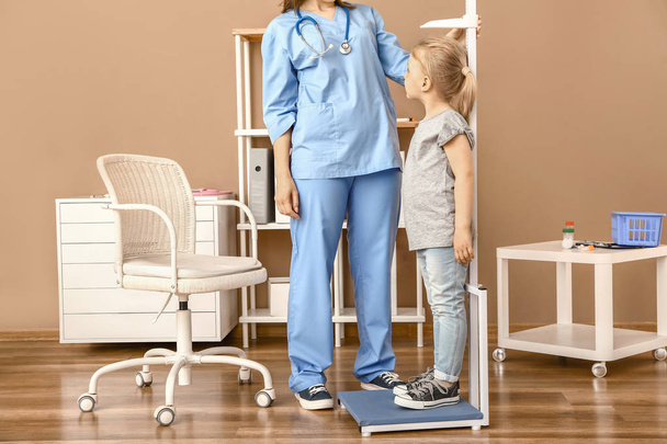 Female nurse measuring height of little girl in hospital - Foto, Imagem
