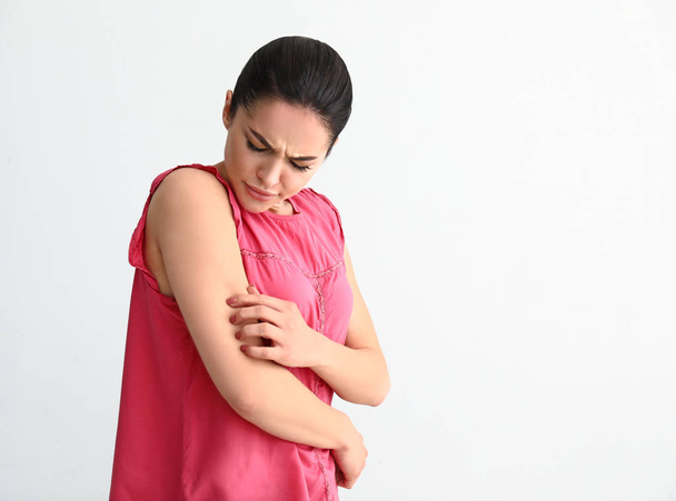 Mujer joven con alergia a la piel sobre fondo claro
 - Foto, Imagen