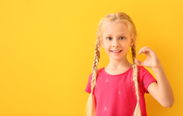 Malá hluchá dívka používající jazyk podepisování na pozadí barev - Fotografie, Obrázek