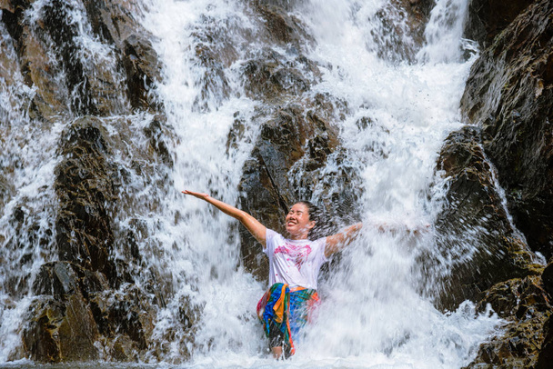 Tyttö matkalla vesiputous lomalla. Tyttö, joka nauttii vesiputouksen pelaamisesta onnellisena. matkailu luonto, Travel rentoutua, matkustaa Thaimaa. Huai Toh vesiputous Krabissa
. - Valokuva, kuva