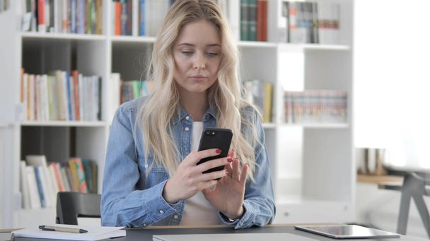 Nuori blondi nainen käyttää älypuhelinta
 - Valokuva, kuva