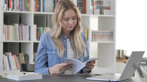 Young Blonde Woman Reading Book in Library - Foto, immagini