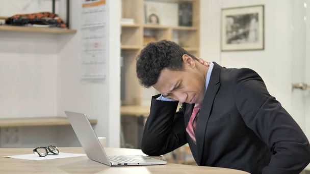 Втомився молодий Африканський бізнесмен з болем у шиї, що працюють на ноутбуці - Фото, зображення
