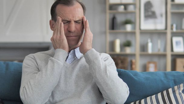 Hombre de mediana edad estresado con dolor de cabeza sentado en el sofá
 - Foto, imagen