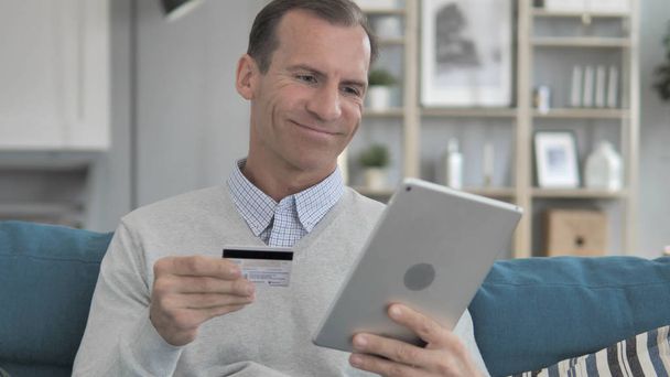 Online vásárlás a Tablet a középkorú ember ül a kanapén - Fotó, kép