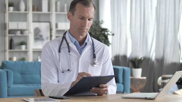 Oberarzt liest medizinische Dokumente des Patienten - Foto, Bild