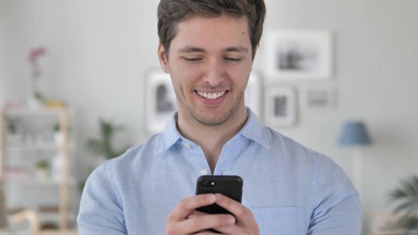 Komea nuori mies kiireinen käyttämällä älypuhelinta
 - Valokuva, kuva