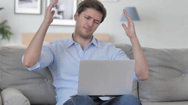 Розроблений літній чоловік реагує на втрату ноутбука сидячи на дивані
 - Фото, зображення
