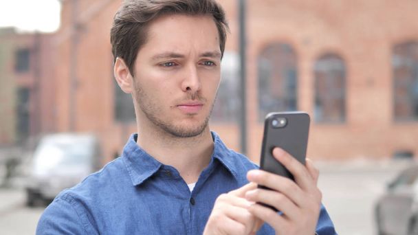 Υπαίθριο πορτραίτο του νεαρού man χρησιμοποιώντας smartphone - Φωτογραφία, εικόνα