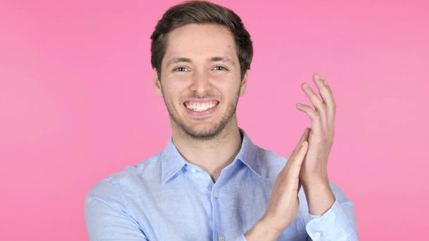 Applauding, jonge man klappen op roze achtergrond - Foto, afbeelding