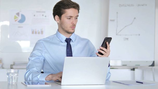 Young Businessman Using Smartphone and Laptop for Work - Foto, immagini