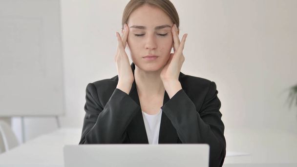 Nahaufnahme einer jungen Geschäftsfrau mit Kopfschmerzen bei der Arbeit am Laptop - Foto, Bild