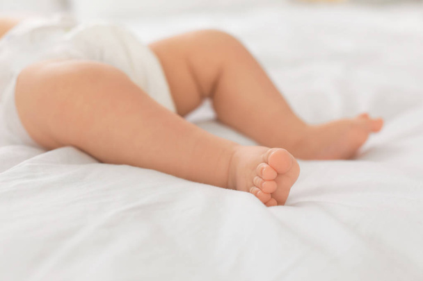 Cute little baby lying on bed, closeup of legs - Zdjęcie, obraz