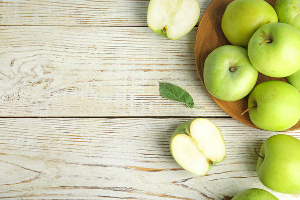 Tasainen lay koostumus tuoreita kypsiä vihreitä omenoita valkoinen puinen pöytä, tilaa tekstiä
 - Valokuva, kuva